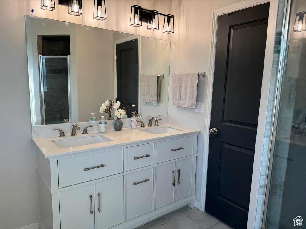 Bathroom featuring double sink vanity, walk in shower, and tile patterned flooring