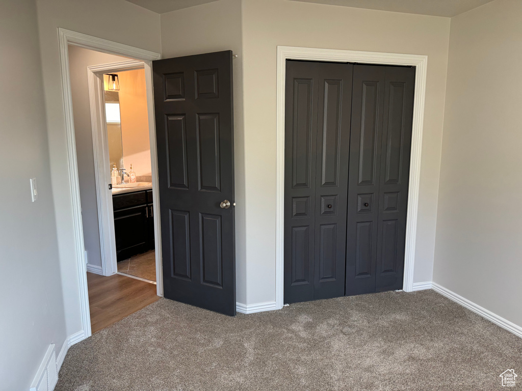 Unfurnished bedroom with carpet floors, sink, and a closet