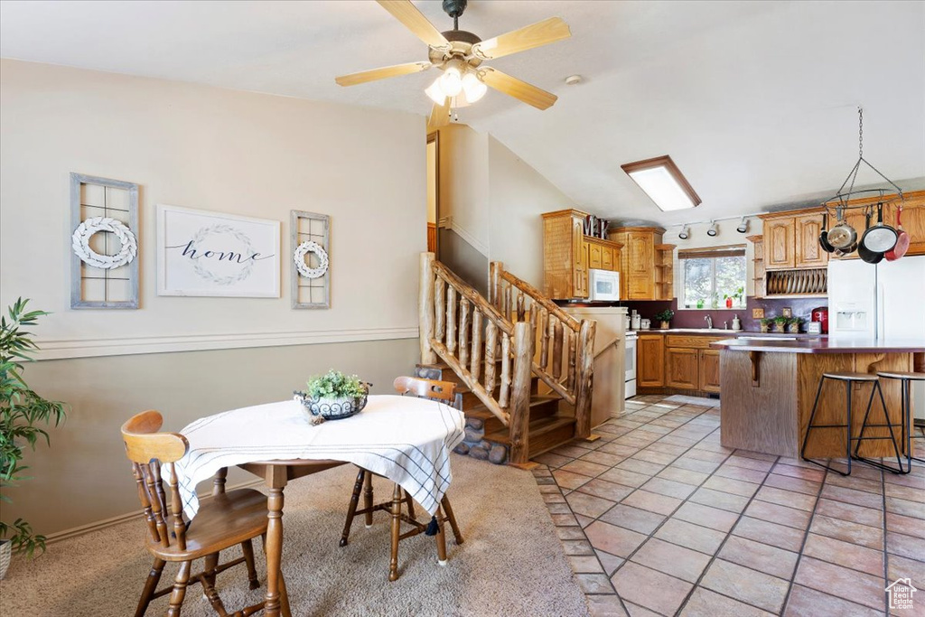 Dining space with ceiling fan, track lighting, vaulted ceiling, and light tile patterned floors