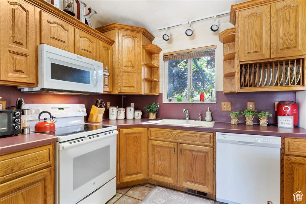 Kitchen with track lighting, sink, white appliances, and light tile patterned floors