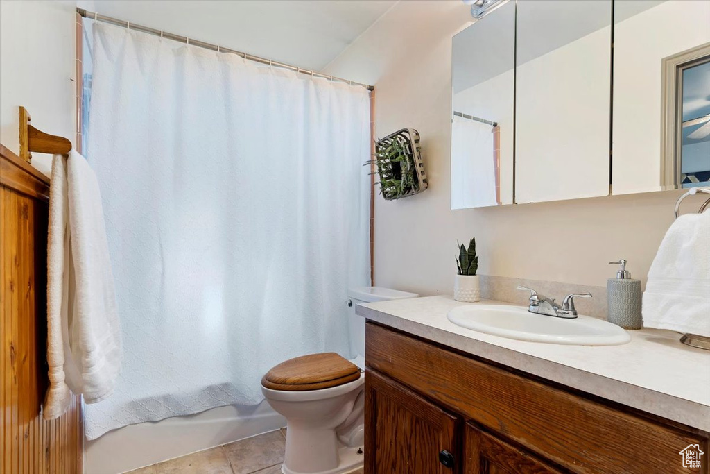 Full bathroom featuring tile patterned flooring, shower / bath combination with curtain, toilet, and vanity