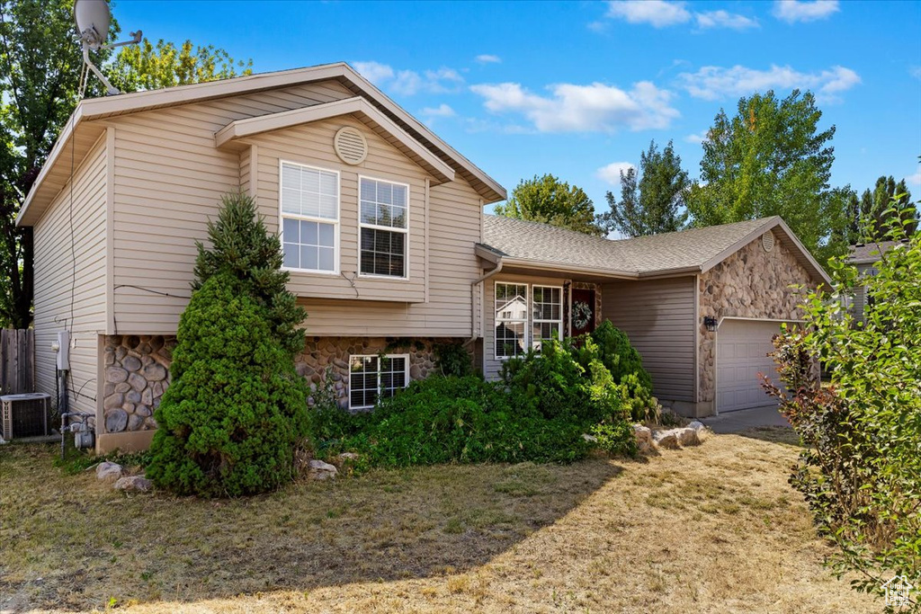 Tri-level home featuring a garage and central air condition unit