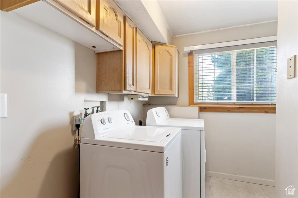 Laundry room featuring cabinets, washer and dryer, and light tile patterned floors