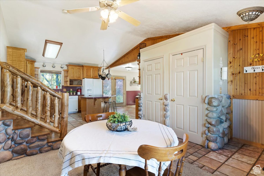 Dining area featuring track lighting, lofted ceiling, light tile patterned floors, and ceiling fan