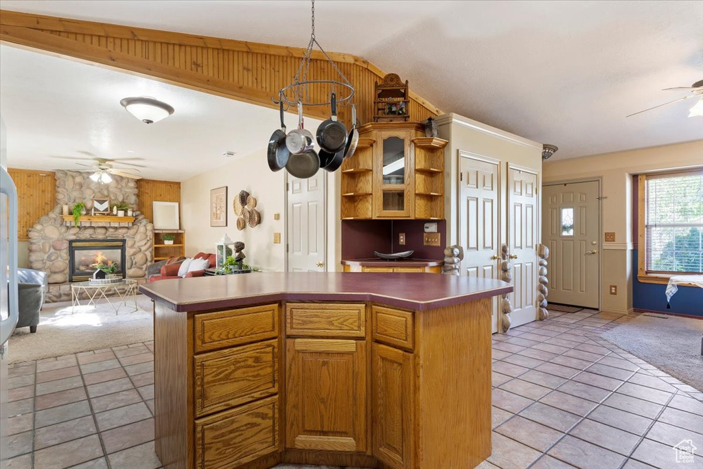 Kitchen featuring a stone fireplace, ceiling fan, lofted ceiling, and light tile patterned floors