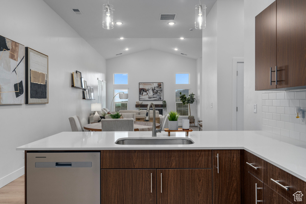 Kitchen featuring sink, dishwasher, light hardwood / wood-style floors, lofted ceiling, and backsplash