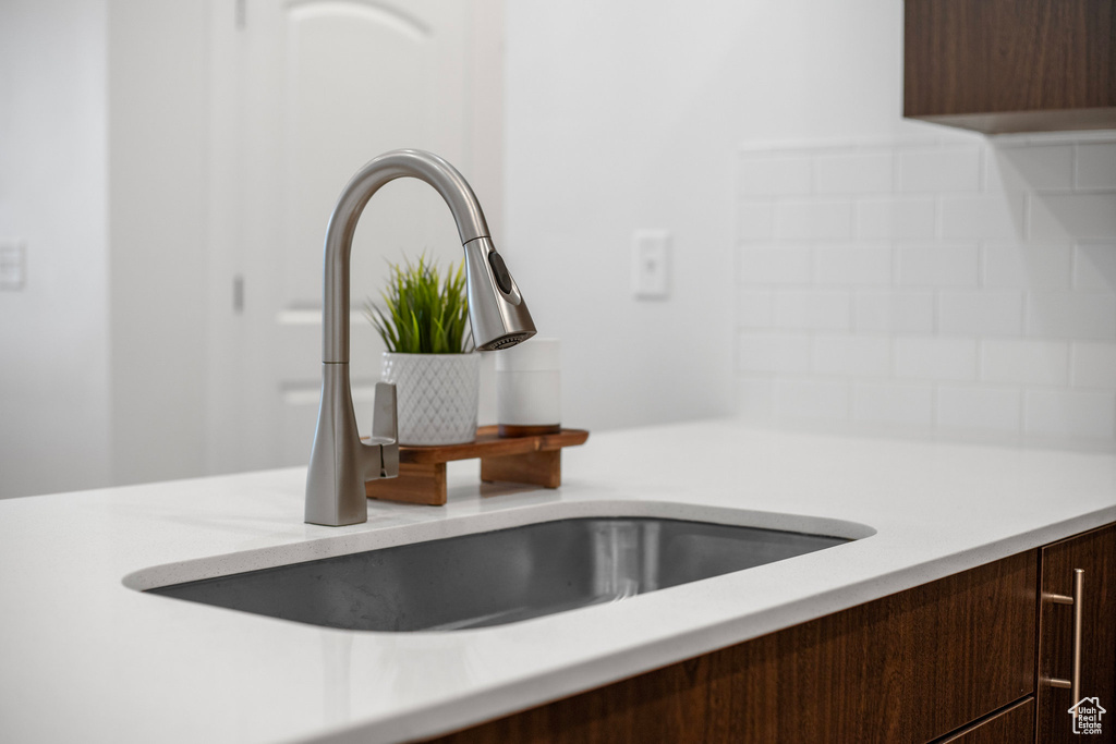 Details with decorative backsplash, dark brown cabinetry, and sink