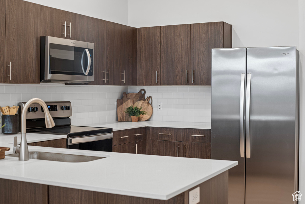 Kitchen featuring dark brown cabinetry, sink, decorative backsplash, and stainless steel appliances