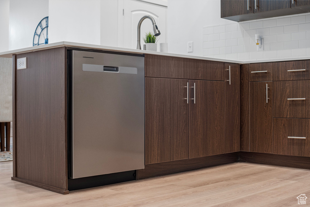 Kitchen with dark brown cabinets, backsplash, dishwasher, and light wood-type flooring