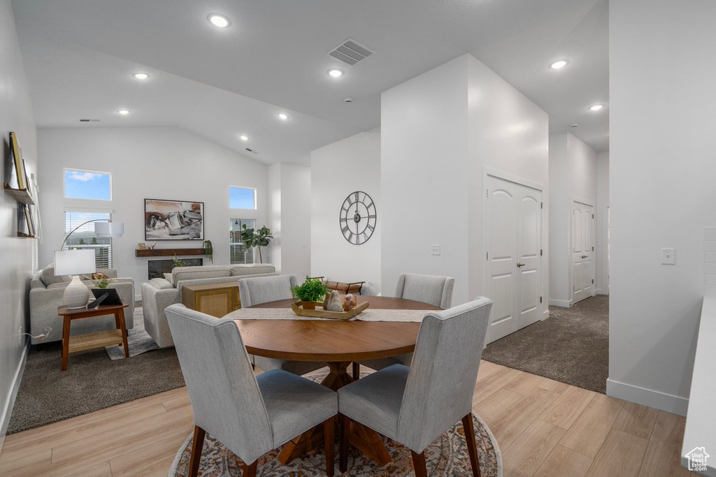 Dining area with light hardwood / wood-style flooring and high vaulted ceiling