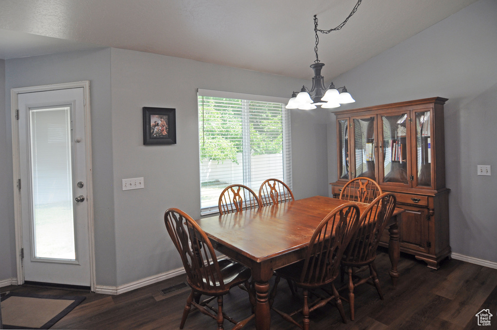 Dining area featuring vaulted ceiling, dark hardwood / wood-style floors, and a chandelier