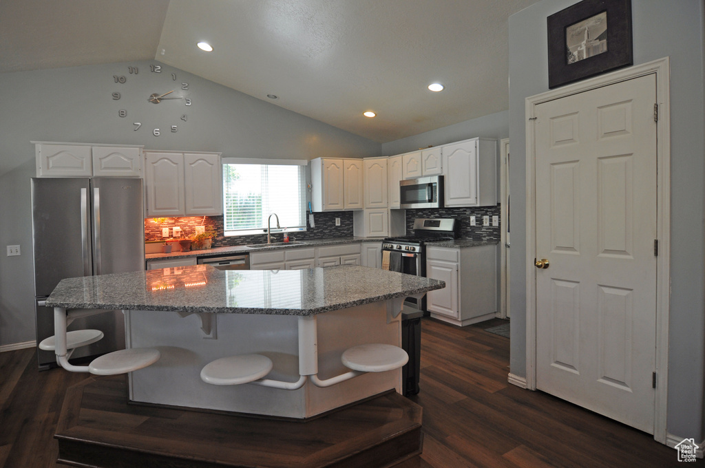 Kitchen featuring a kitchen island, appliances with stainless steel finishes, dark hardwood / wood-style floors, and white cabinets