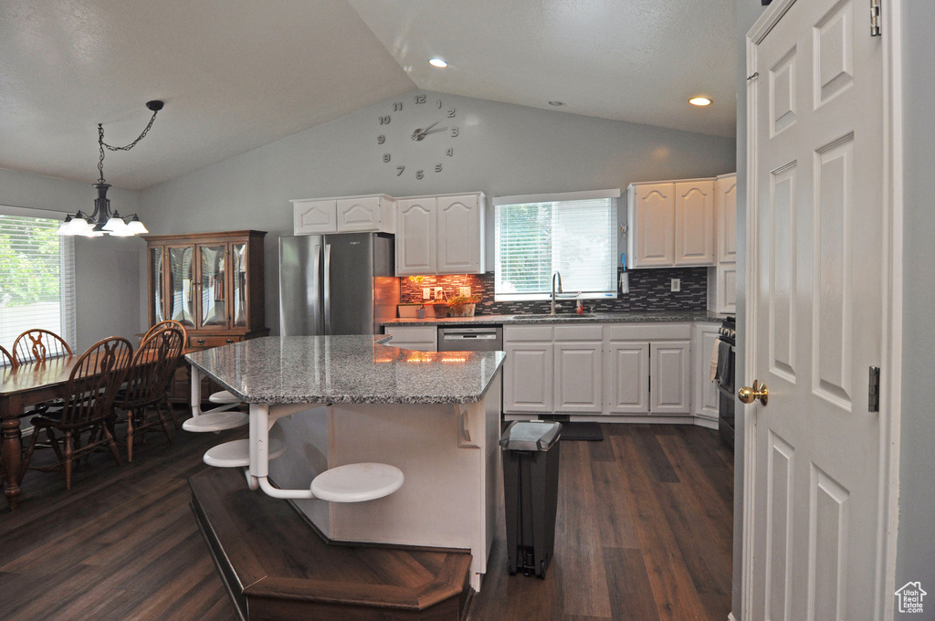 Kitchen with white cabinetry, dark wood-type flooring, stainless steel appliances, decorative backsplash, and sink