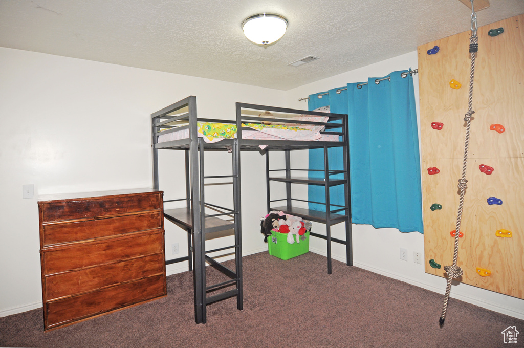 Unfurnished bedroom with dark colored carpet and a textured ceiling