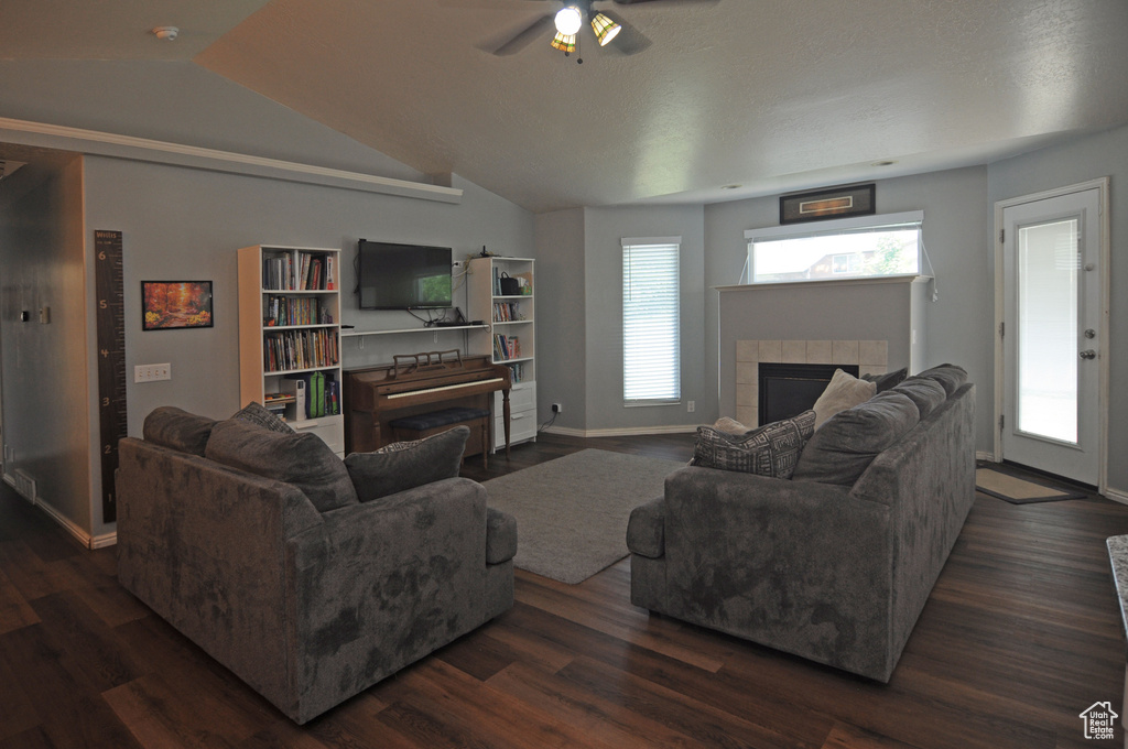 Living room featuring dark wood-type flooring, a tile fireplace, and ceiling fan