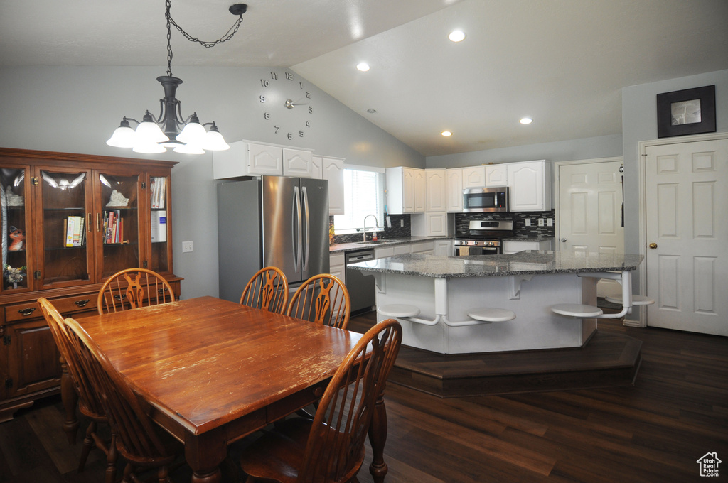 Dining room with sink, a chandelier, high vaulted ceiling, and dark wood-type flooring