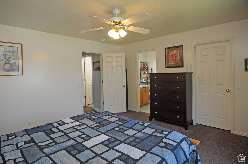 Bedroom with dark colored carpet, ceiling fan, and connected bathroom