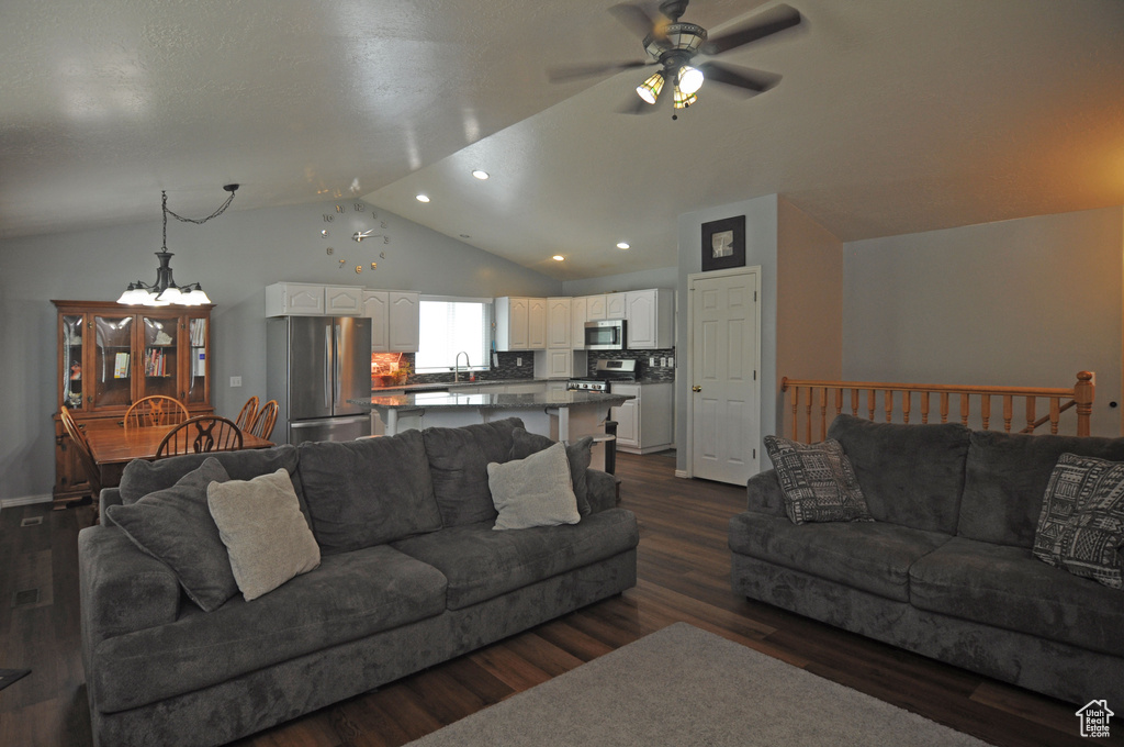 Living room featuring sink, dark wood-type flooring, ceiling fan with notable chandelier, and vaulted ceiling