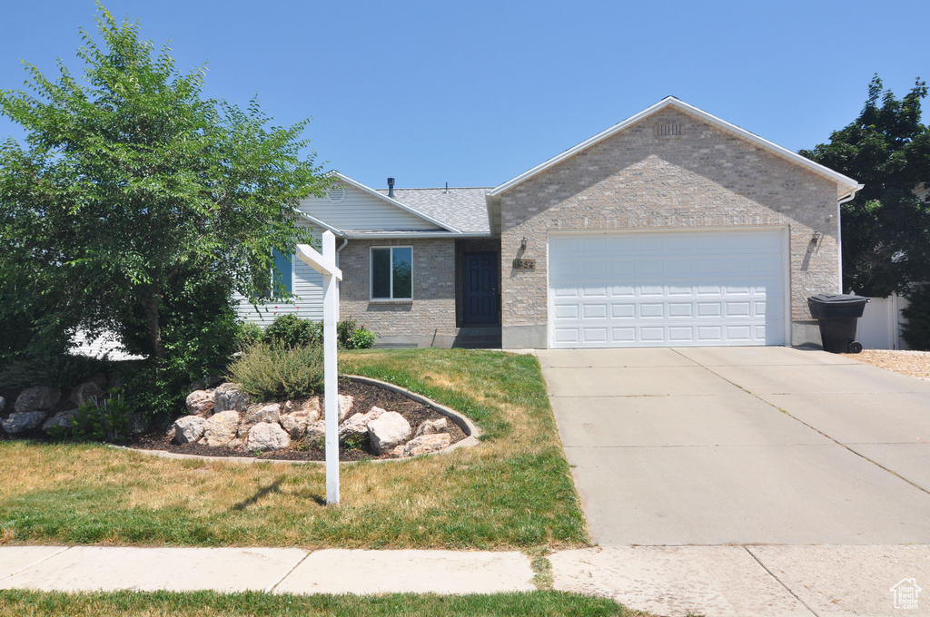 Ranch-style house featuring a garage and a front yard