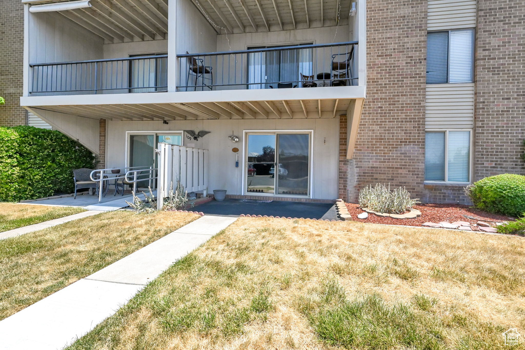 Exterior space featuring a patio, a balcony, and a yard