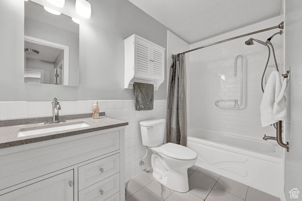 Full bathroom with tile patterned flooring, toilet, shower / bathtub combination with curtain, and vanity