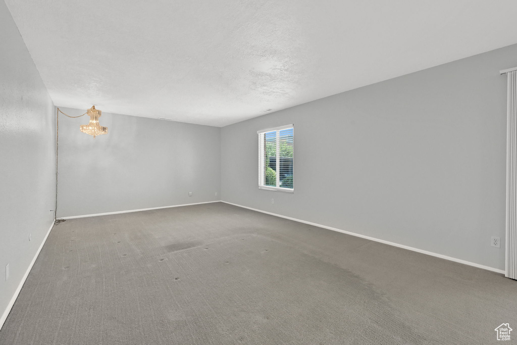 Carpeted spare room with a notable chandelier