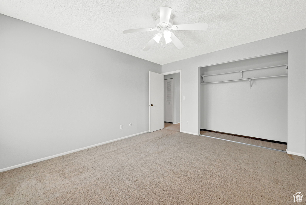 Unfurnished bedroom featuring a textured ceiling, carpet floors, and ceiling fan