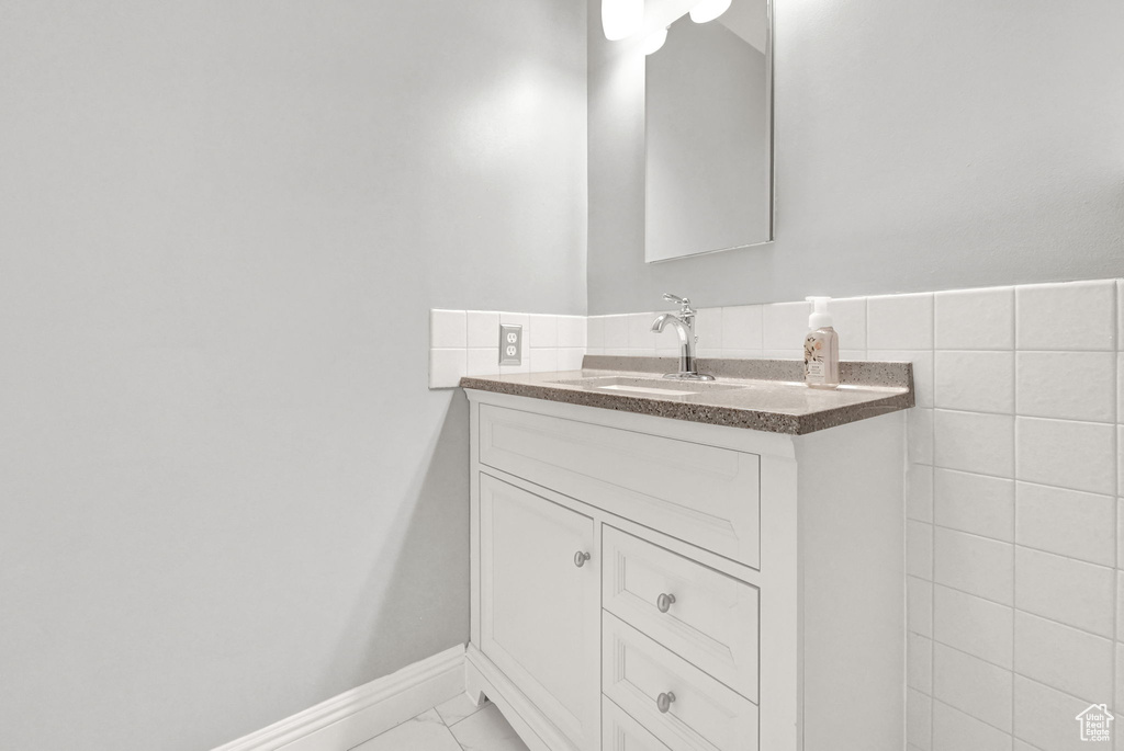 Bathroom featuring vanity, backsplash, tile walls, and tile patterned floors