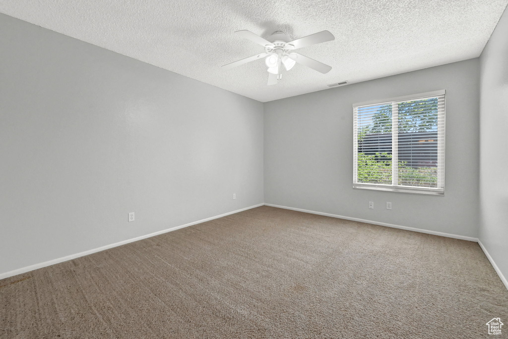 Carpeted spare room featuring a textured ceiling and ceiling fan