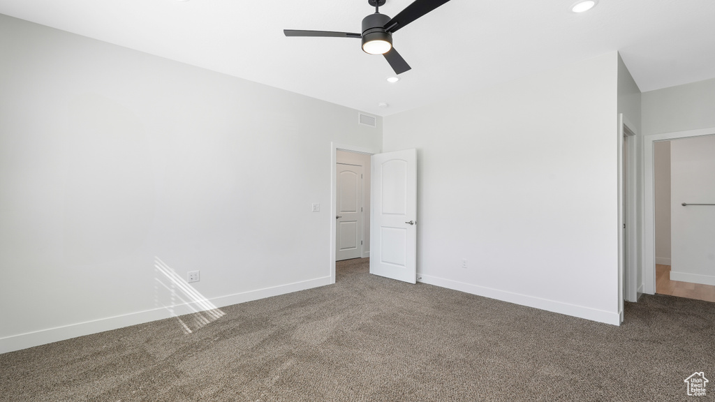 Unfurnished bedroom with ceiling fan and dark carpet