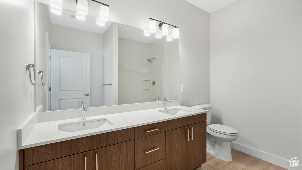 Bathroom with hardwood / wood-style flooring, toilet, and dual bowl vanity