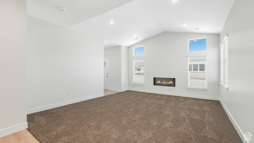 Unfurnished living room featuring lofted ceiling, hardwood / wood-style flooring, and plenty of natural light