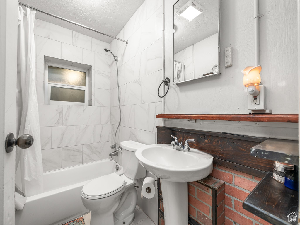 Bathroom featuring tile patterned floors, toilet, shower / bathtub combination with curtain, and a textured ceiling