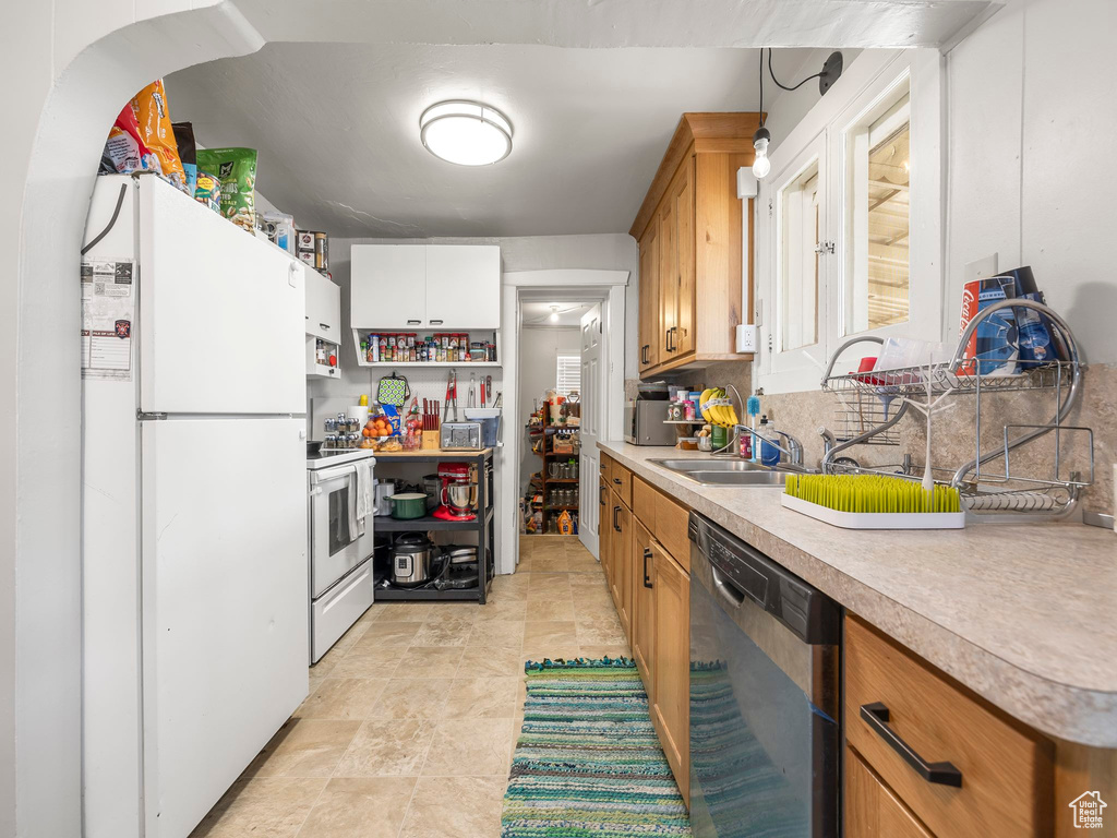 Kitchen featuring sink, white appliances, backsplash, and light tile patterned floors