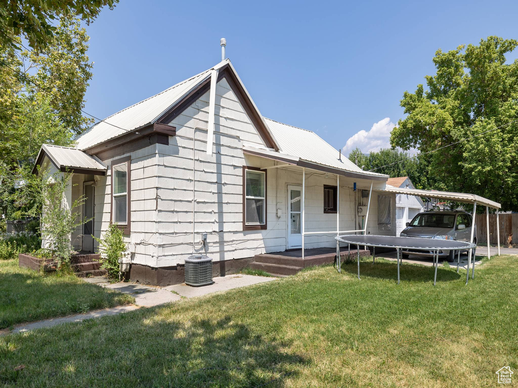 View of front of home with central AC and a front yard