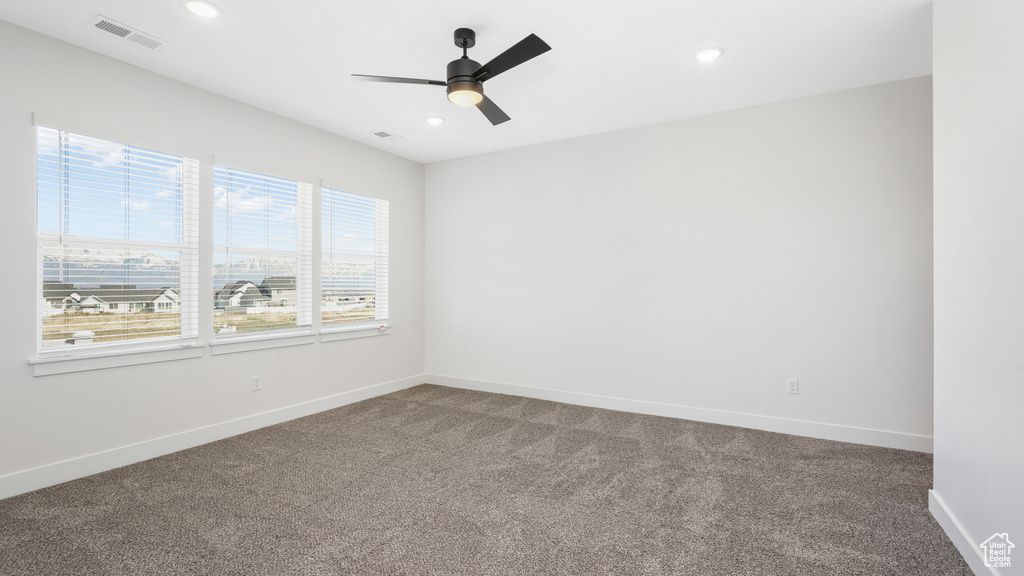 Spare room featuring dark colored carpet and ceiling fan