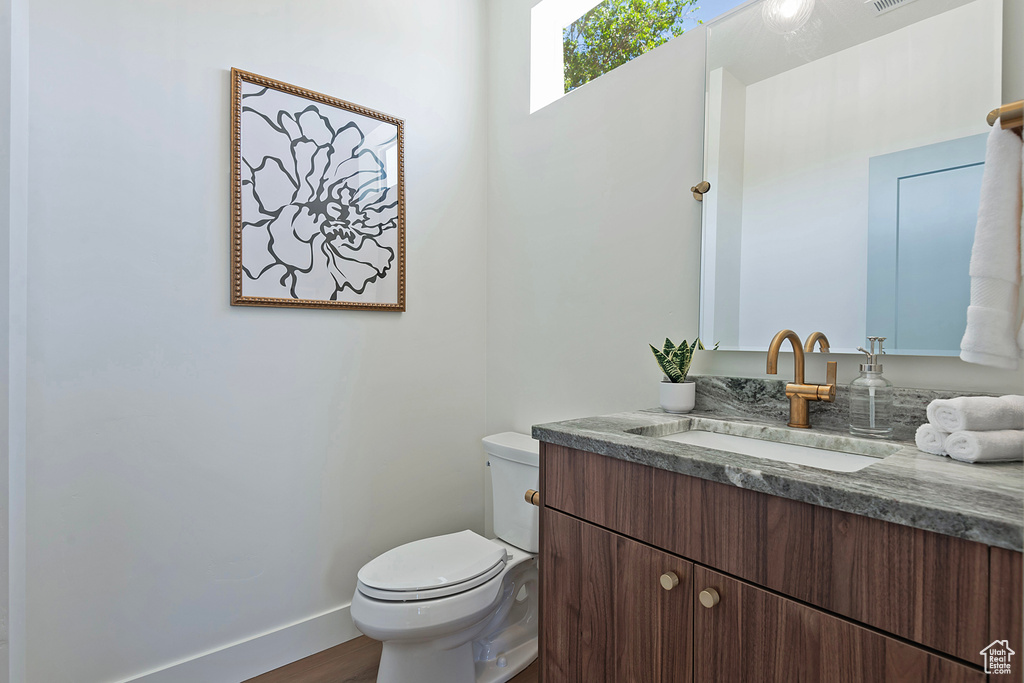 Bathroom featuring vanity, wood-type flooring, and toilet