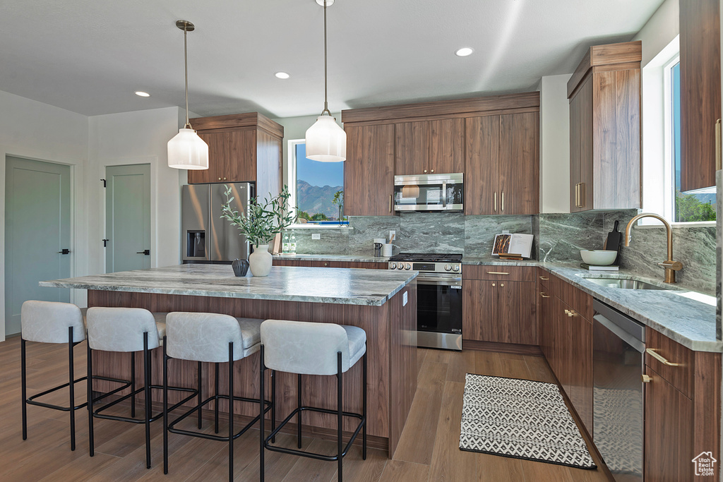 Kitchen featuring decorative light fixtures, stainless steel appliances, hardwood / wood-style floors, sink, and a kitchen island