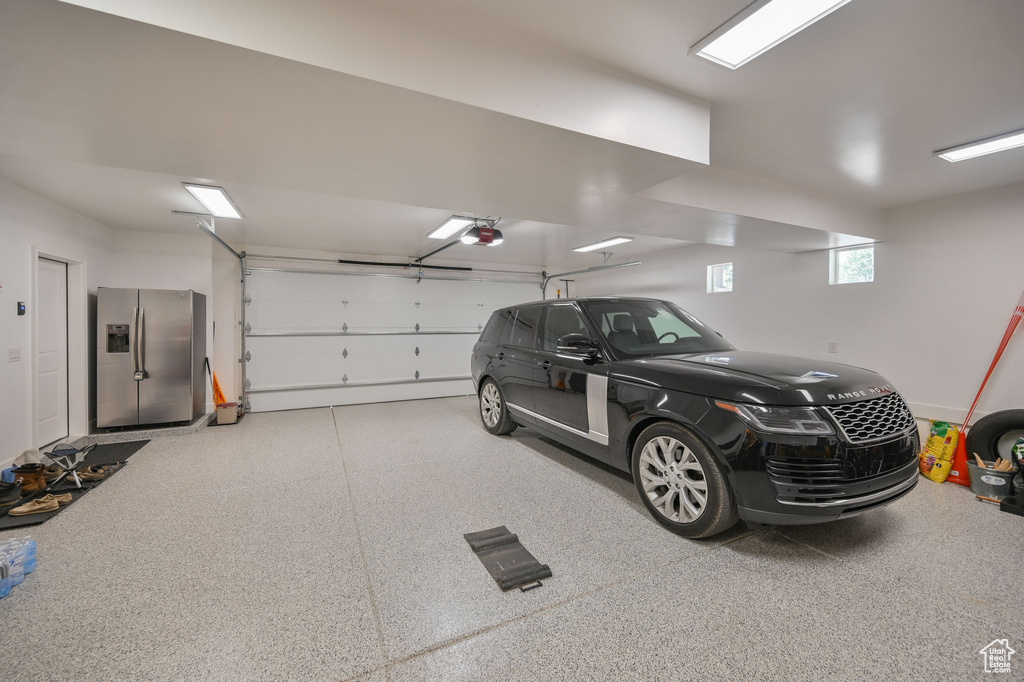 Garage with stainless steel refrigerator with ice dispenser and a garage door opener