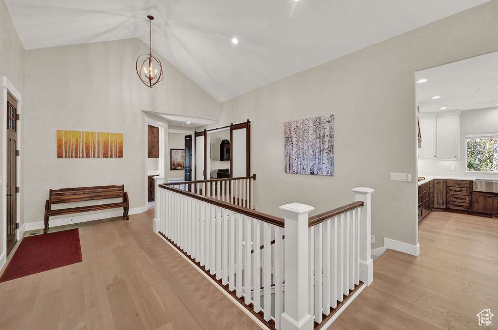 Hall featuring an inviting chandelier, high vaulted ceiling, and light wood-type flooring