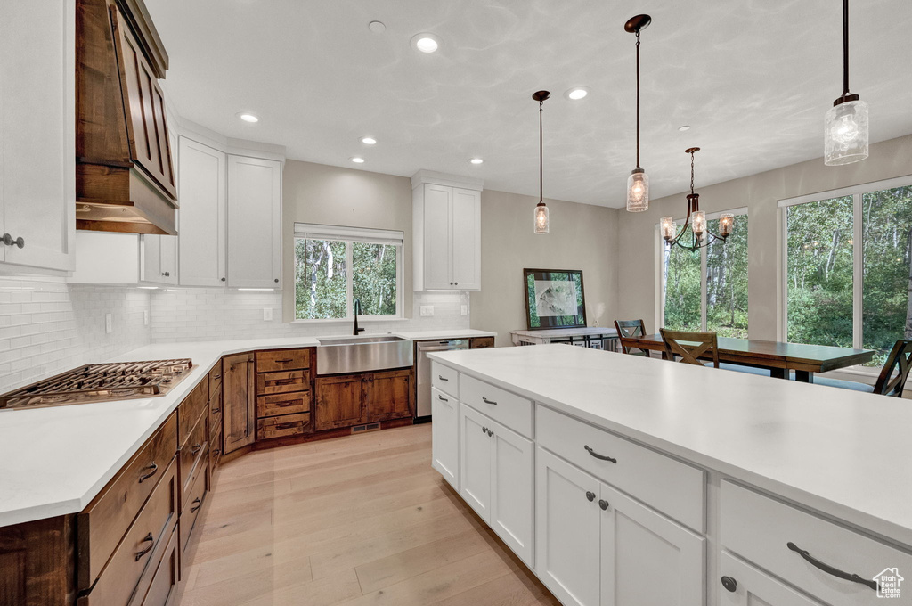 Kitchen with sink, pendant lighting, white cabinets, and backsplash