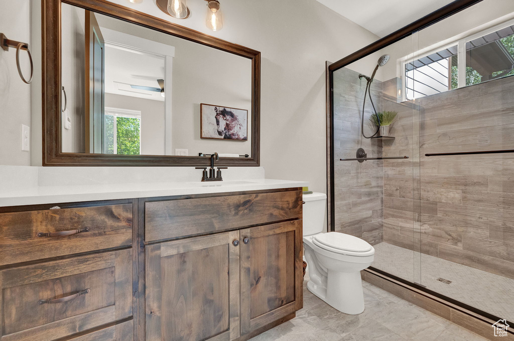 Bathroom featuring vanity, tile patterned floors, ceiling fan, a shower with shower door, and toilet