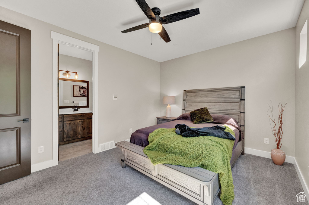 Carpeted bedroom featuring connected bathroom and ceiling fan