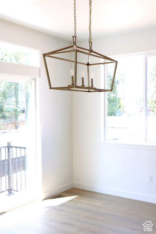 Unfurnished dining area with hardwood / wood-style flooring and a notable chandelier