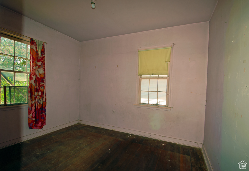 Empty room featuring a wealth of natural light and dark hardwood / wood-style floors
