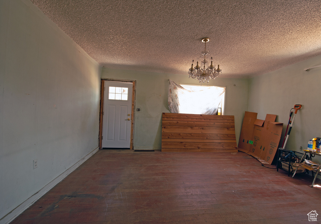 Foyer entrance with a textured ceiling, wood-type flooring, and a notable chandelier