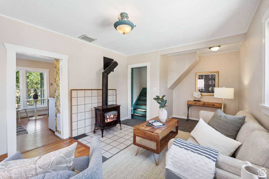 Living room featuring crown molding, light hardwood / wood-style floors, and a wood stove