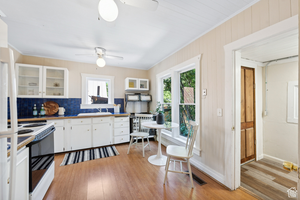 Kitchen featuring white cabinetry, a healthy amount of sunlight, white electric range oven, and ceiling fan