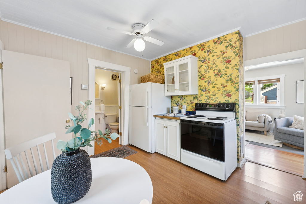 Kitchen featuring white cabinets, light hardwood / wood-style floors, and white appliances