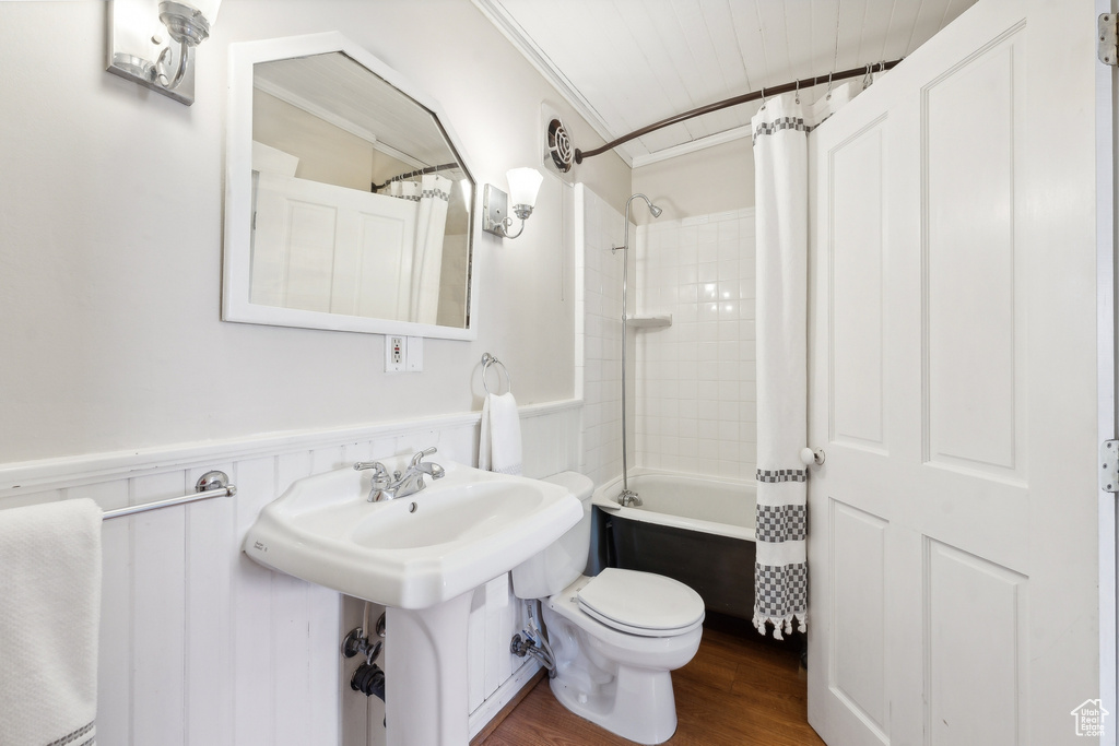 Bathroom with wood-type flooring, shower / bath combo, toilet, and ornamental molding